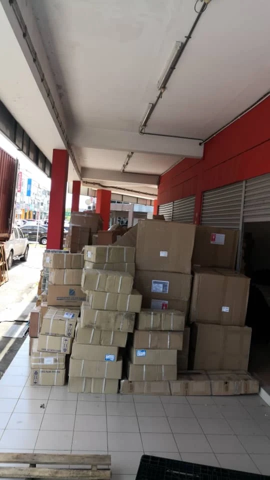 Cartons stacked on a tiled walkway beside a shuttered storefront entrance