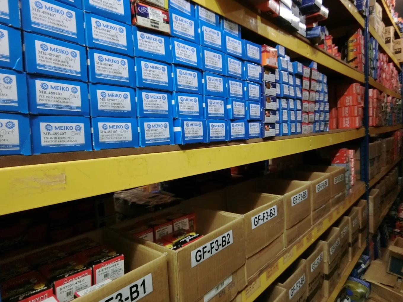 Yellow racks holding labelled cartons of tie rod ends and related steering parts