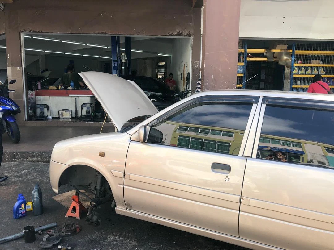 Silver hatchback raised on a jack stand with its front wheel removed during maintenance