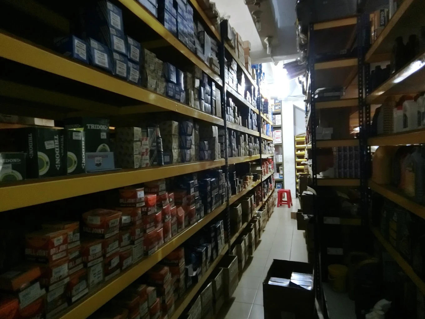 Yellow shelving filled with small boxed automotive parts in a storage aisle